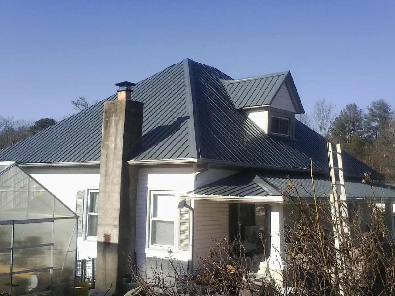 Dark blue standing seam metal roof on a white farmhouse with dormer — Slate & Tile Roof Repair by Roofing Brothers in Ulmer