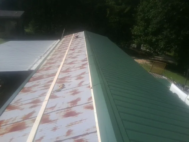 Old rusted panels beside newly installed green metal roofing — Wind Damage Roof Repair by Roofing Brothers in Ulmer