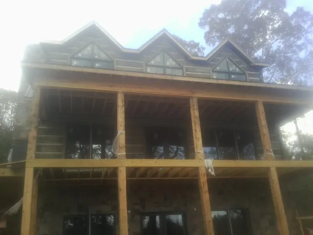 Dormers and porch framing on a large log home under construction — Roof Coating work by our crew in Ulmer