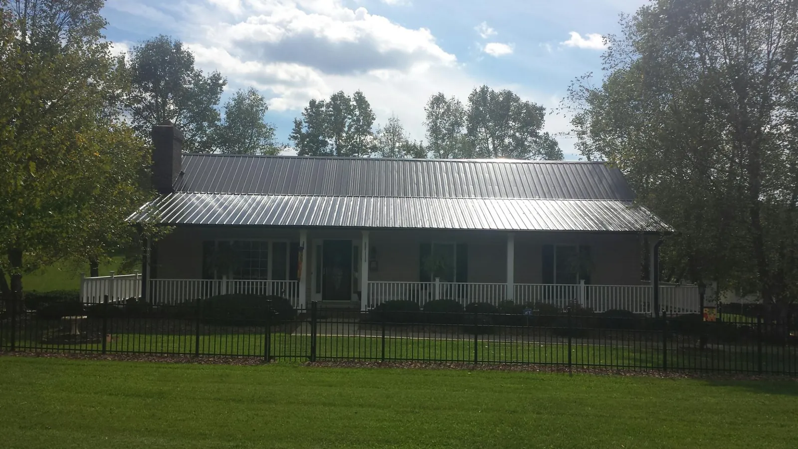 Gray metal roof on a brick ranch with a full width front porch — Gutter Guard Installation work by our crew in Ulmer