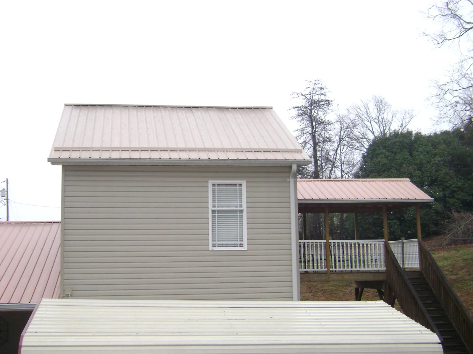 Tan metal roofs on a two story addition and attached porch, from a Roof Replacement job in Ulmer