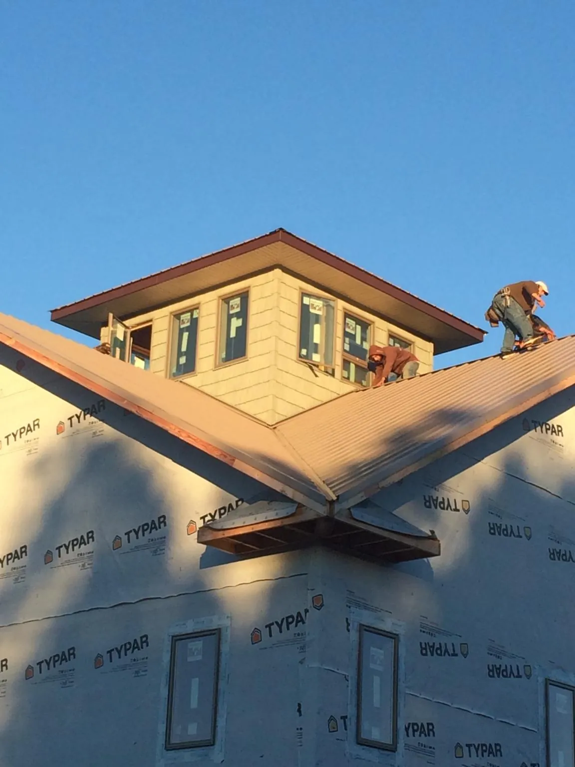Roofers working around a rooftop cupola on a new metal roof at sunset — Roof Waterproofing in Ulmer by Roofing Brothers